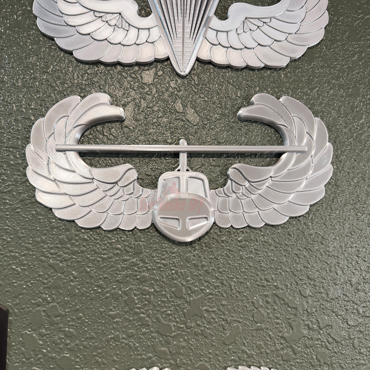 Air Assault Badge display insignia mounted on a wall, showcasing shiny silver finish and wings design.