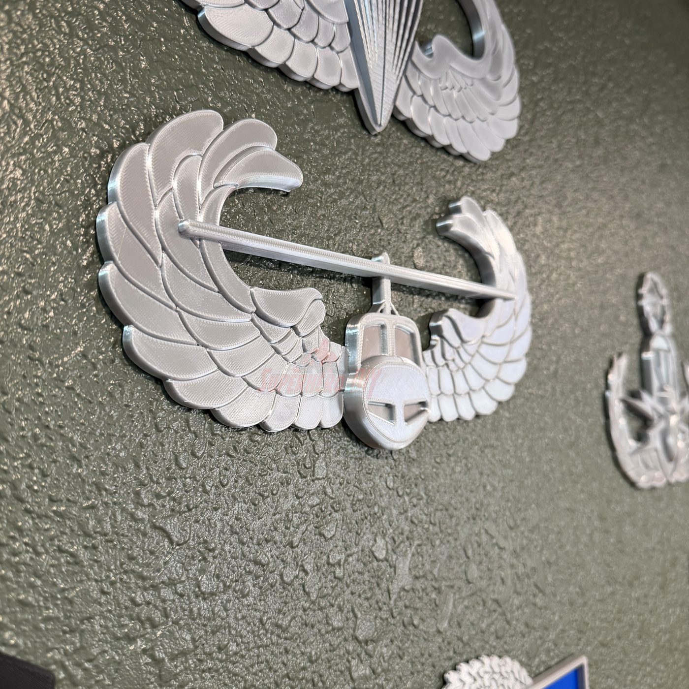 Air Assault Badge display with shiny silver finish mounted on wall.