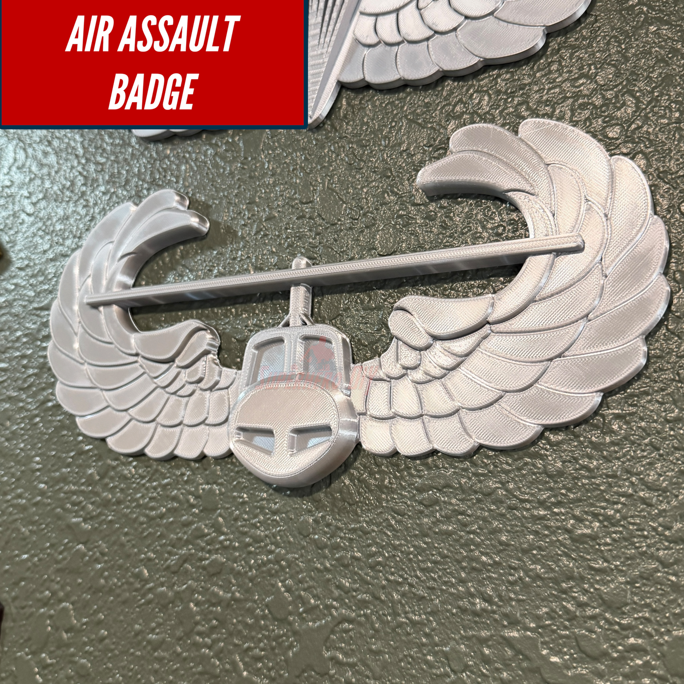 Air Assault Badge display featuring a shiny silver finish with wings mounted on a wall.