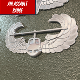 Air Assault Badge display featuring a shiny silver finish with wings mounted on a wall.