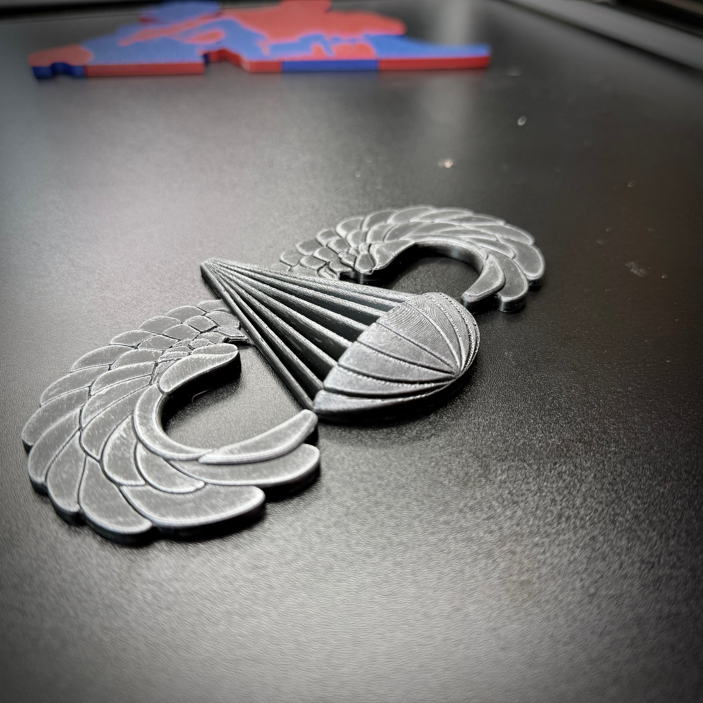 Airborne badge jump wings displayed on a black surface, representing achievement and courage.