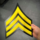 Army enlisted rank insignia in bold yellow and black design, representing the Sergeant rank.