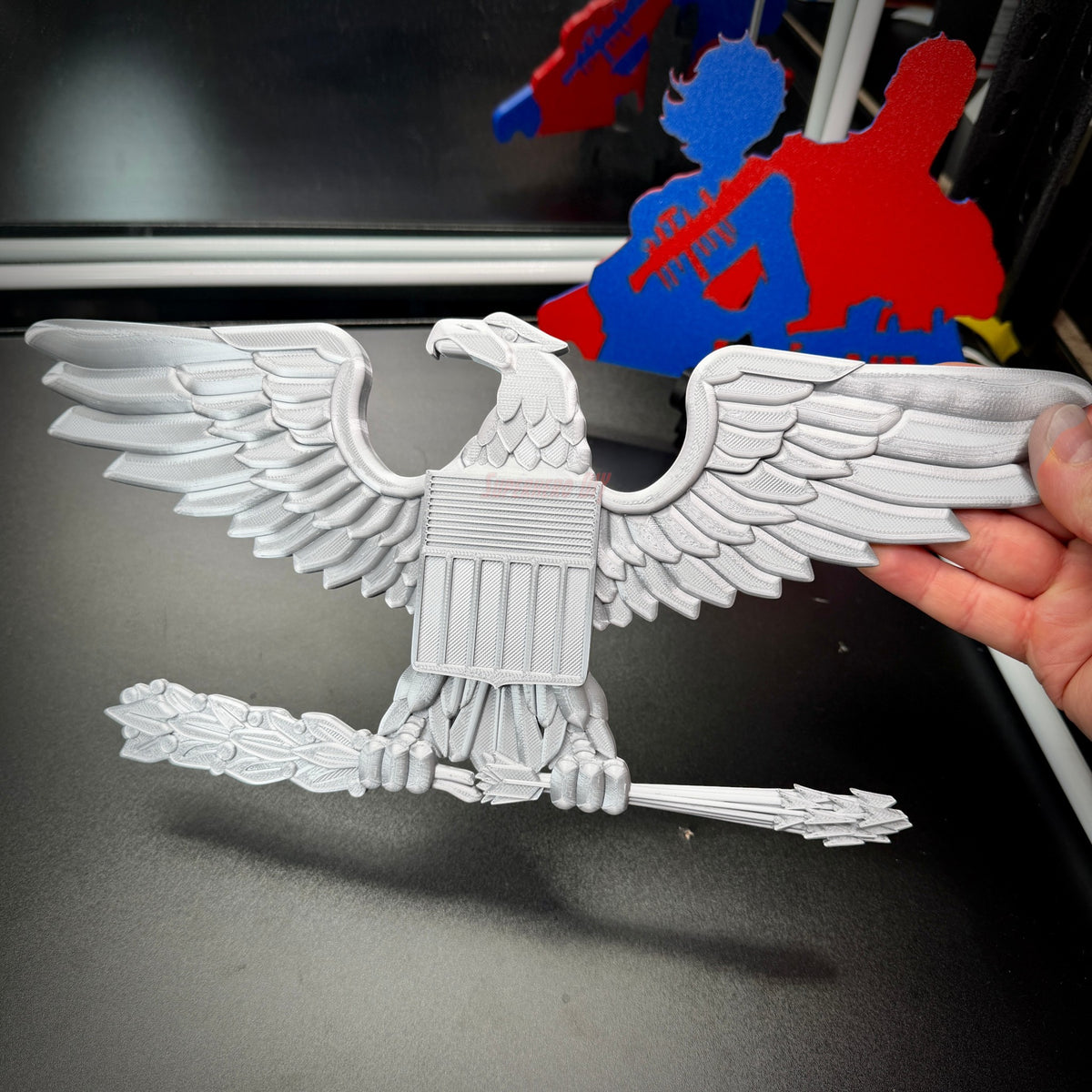 Hand holding a detailed eagle emblem in gray, symbolizing U.S. military insignia, perfect for collectors and display.