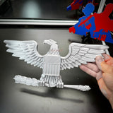 Hand holding a detailed eagle emblem, showcasing military insignia craftsmanship in gray color.