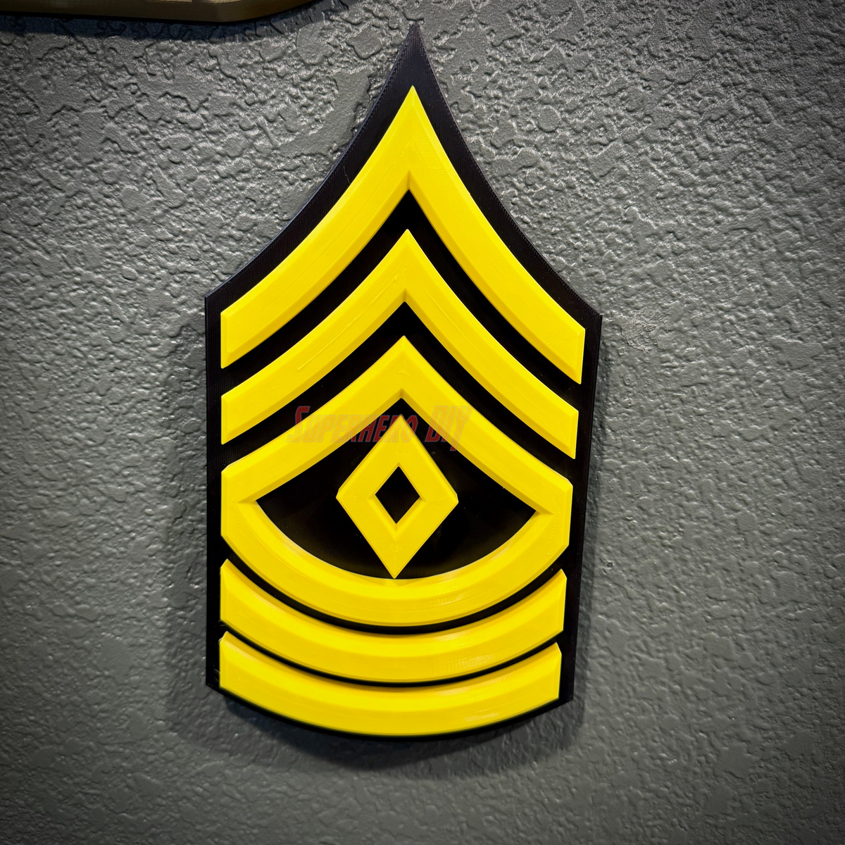 3D-printed Army enlisted rank insignia in yellow, representing a Sergeant rank