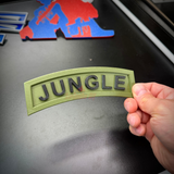 Person holding a green 3D jungle tab with black lettering, showcasing the word JUNGLE in a curved design.