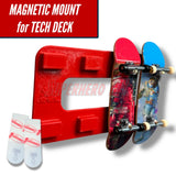 Red magnetic Tech Deck wall mount holding two fingerboards with included adhesive strips