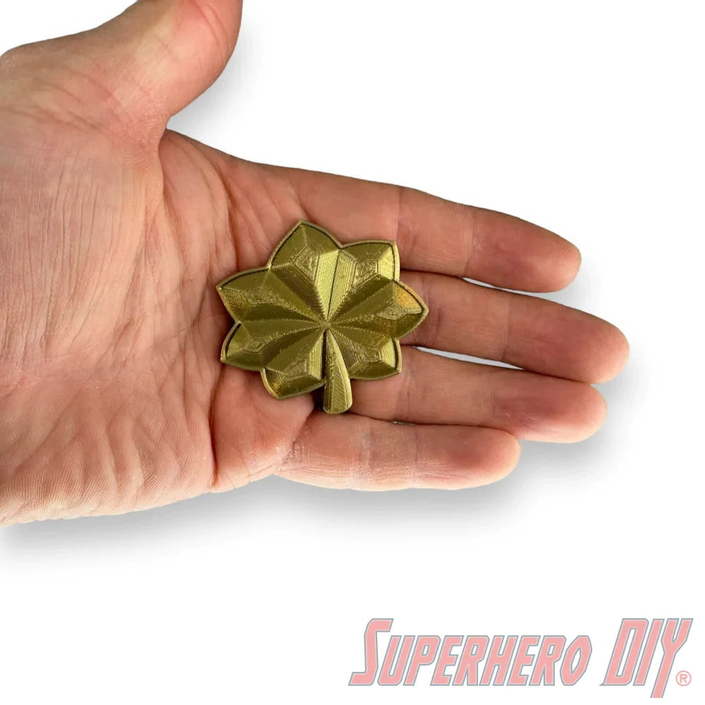 O-4 Major Navy lieutenant commander rank insignia in a gold silk finish held in a hand.