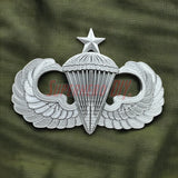 Silver replica Jump Wings badge on green fabric background.