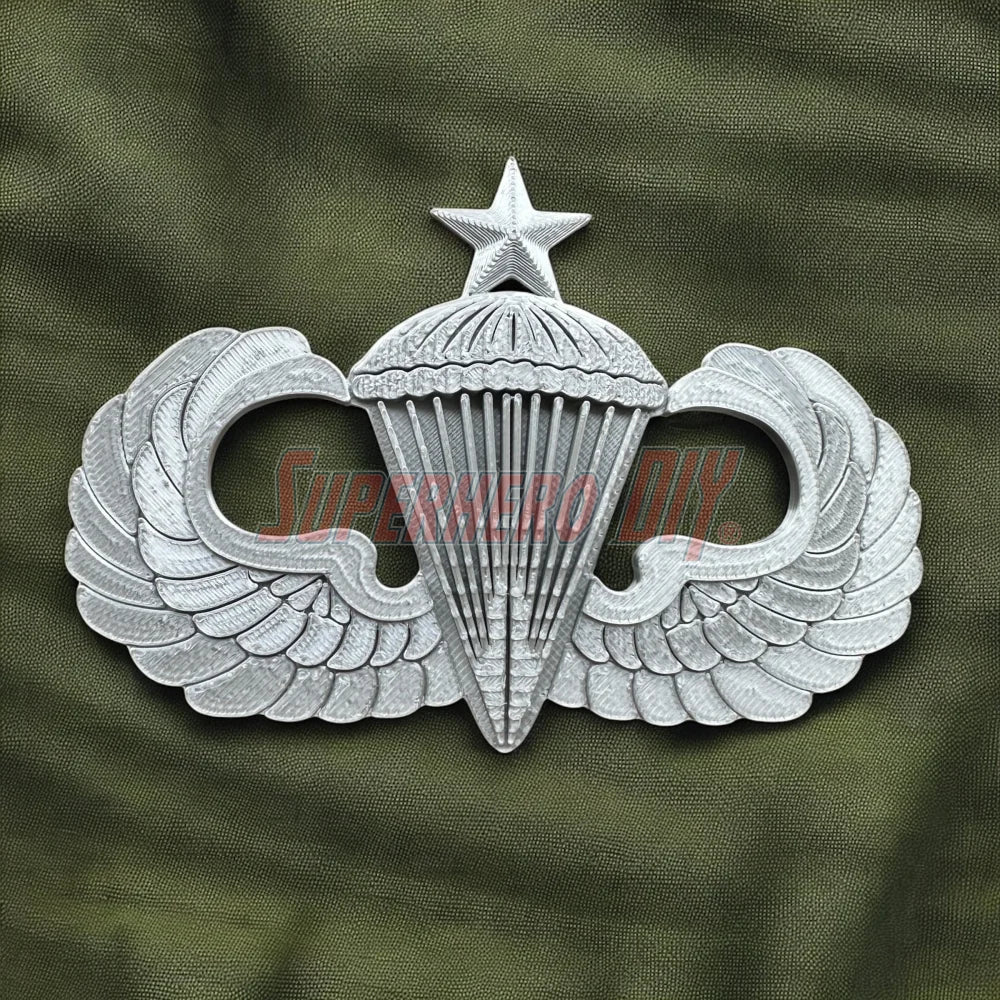 Silver replica Jump Wings badge on green fabric background.