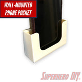Wall-mounted phone holder with phone displayed, featuring a sleek white design, ideal for hands-free convenience in bathroom or office spaces.