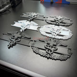 Army medical badge display insignia with EFMB, CMB, and MCMB designs on a table surface.