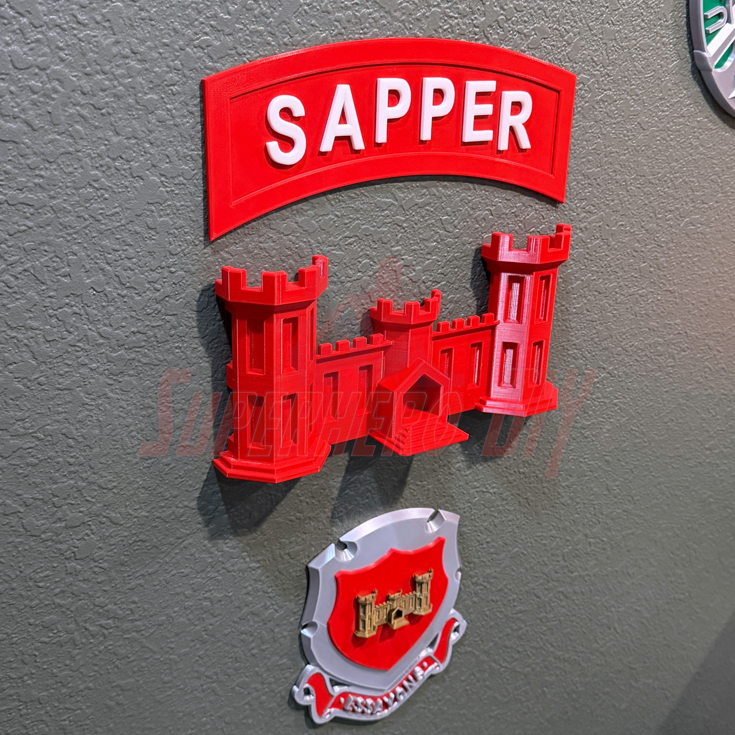 3D sapper tab display piece featuring a red 'SAPPER' sign and castle design on a wall.
