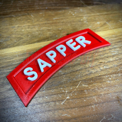 3D Sapper Tab in red with white lettering on a wooden surface, showcasing combat engineer achievement.
