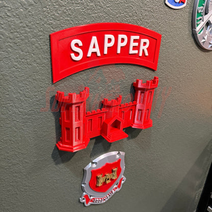 3D sapper tab displayed on a surface showcasing the red Sapper emblem and castle design.