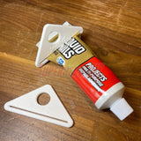Simple Tube Squeezer efficiently squeezing a tube of Liquid Nails adhesive on a wooden surface.