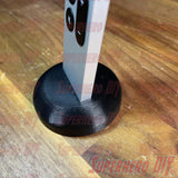 Apple TV Remote Stand holding Siri Remote upright on wooden surface, 3D-printed design.