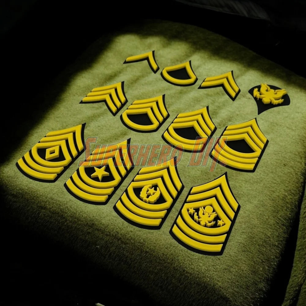 Multiple Army enlisted rank insignia patches in yellow displayed on a textured surface.