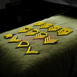 Multiple U.S. Army enlisted rank insignia displayed on a green surface, featuring various ranks and sizes.