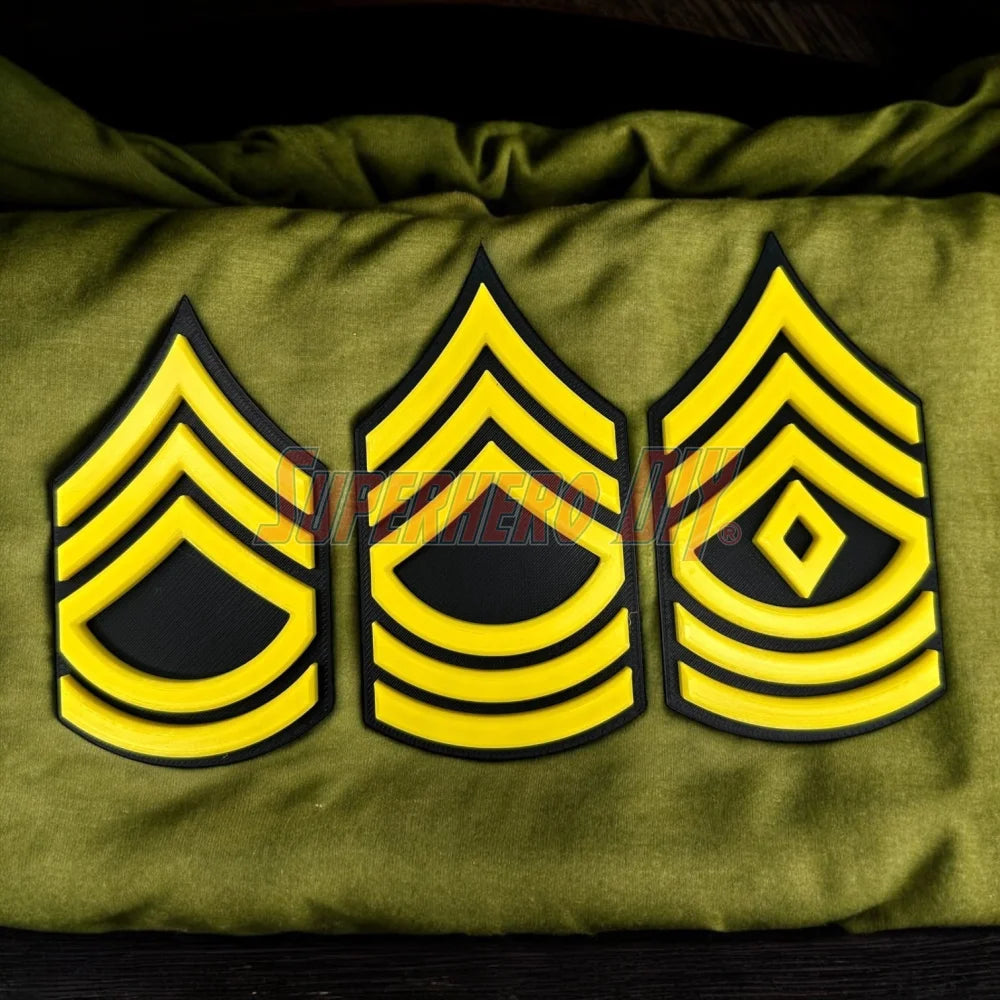 Army enlisted rank insignia with three 3D-printed yellow and black patterns displayed on a green fabric.