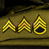 Army enlisted rank insignia showing three stripes with yellow accents on a green background.
