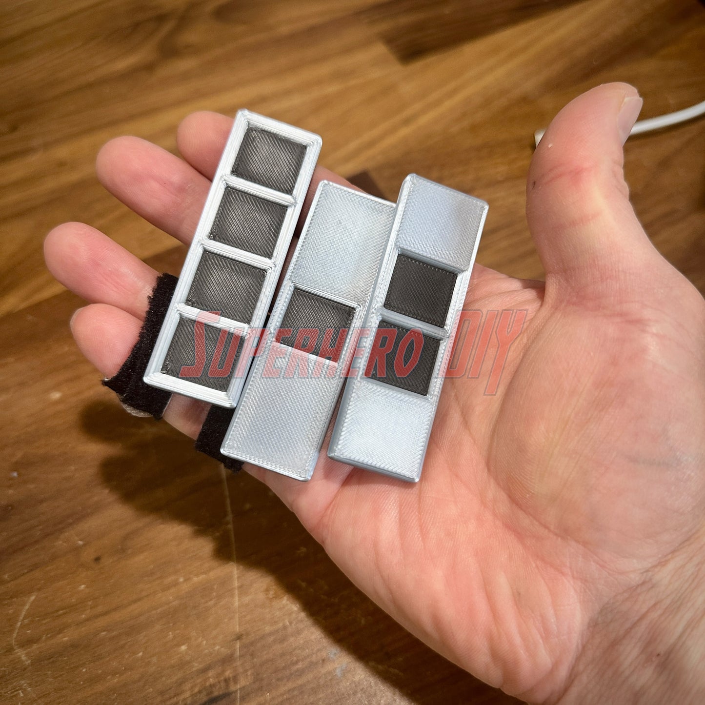 Hand holding 3D replicas of US Army Warrant Officer Rank Insignia in black and silver, multiple sizes available.