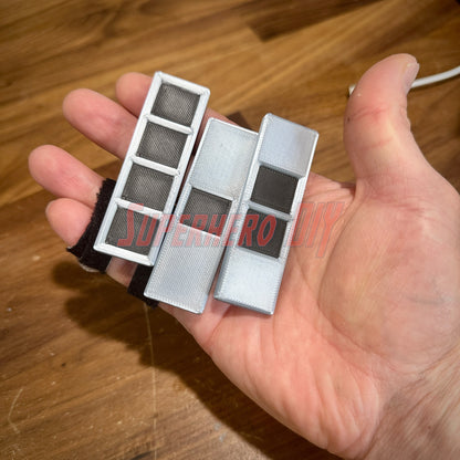 Hand holding 3D replicas of US Army Warrant Officer Rank Insignia in black and silver, multiple sizes available.