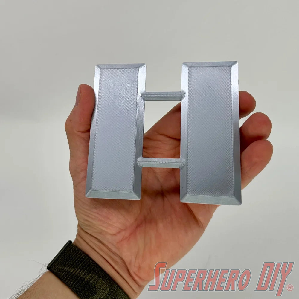 Silver metal US military lieutenant colonel rank insignia held in hand with plain gray background. - SuperheroDIY