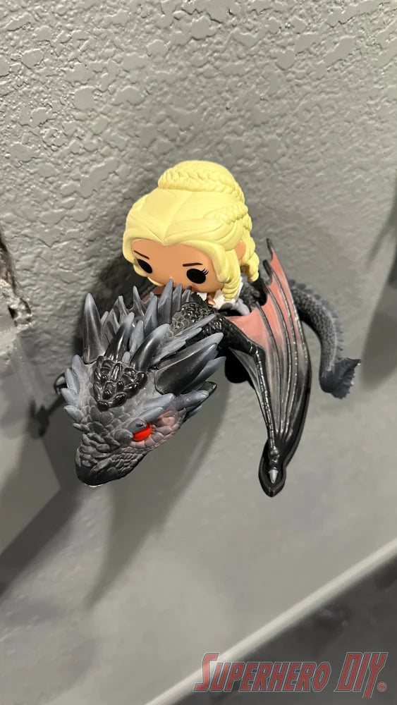 Black wall mount shaped like a Menacing dragon head holding a Funko Pop figure of a blonde woman riding it. - SuperheroDIY