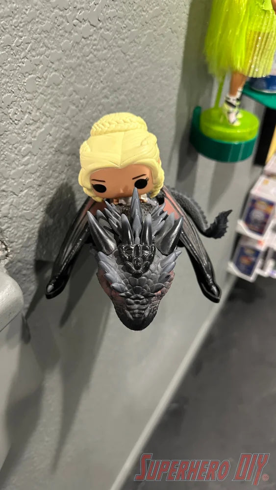 Black wall mount shaped like a dragon head holding a blonde Funko Pop figure with black wings. - SuperheroDIY
