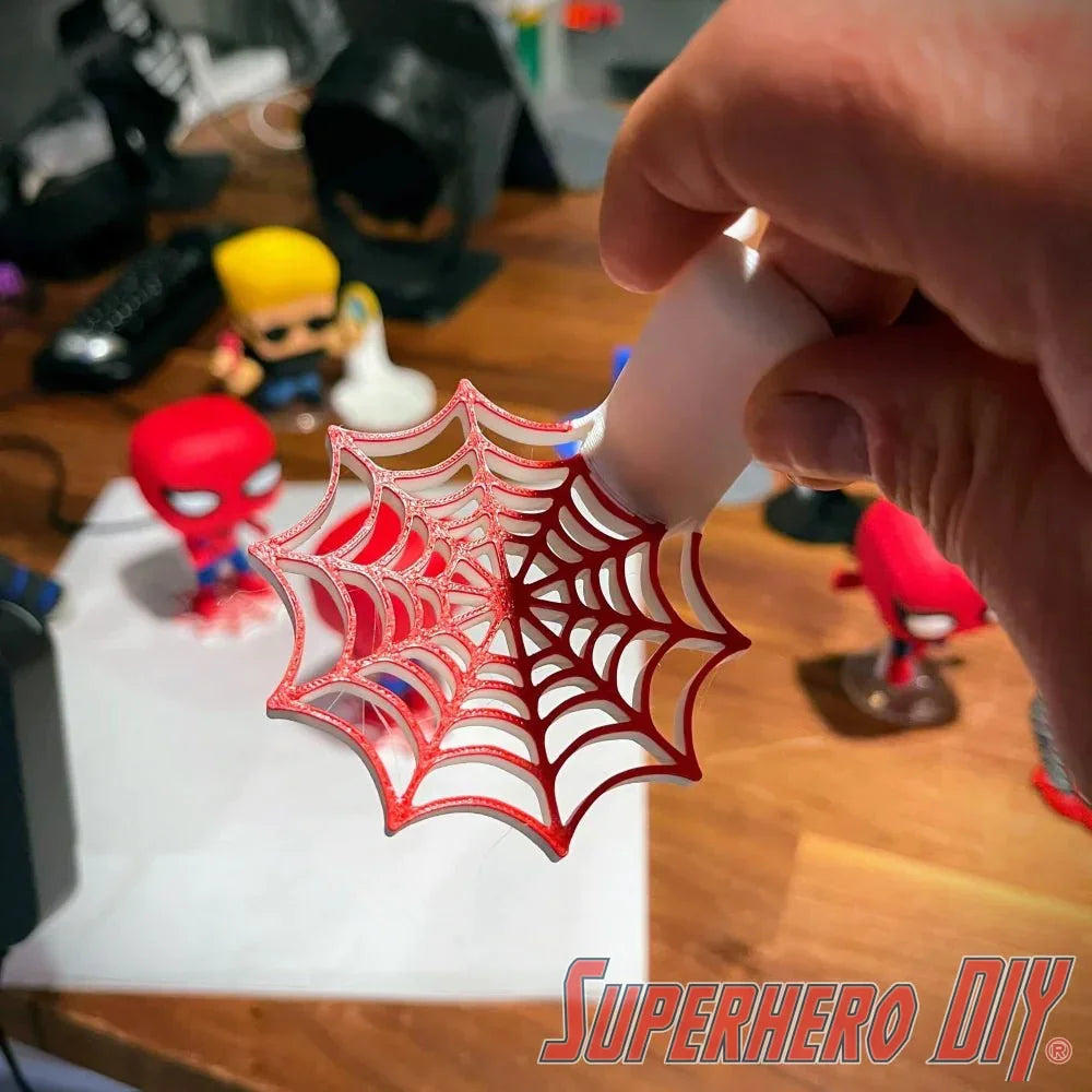 Person holding a wall-mounted web shelf designed for Spider-Man Funko Pop figures, showcasing a unique web pattern.