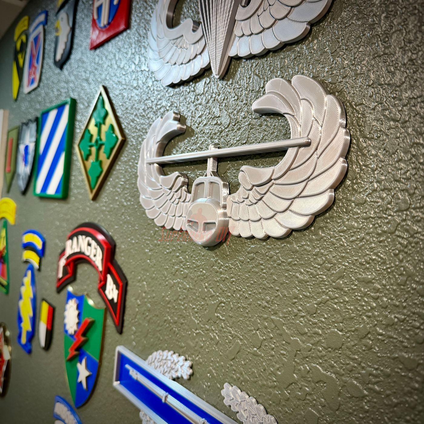 Air Assault Badge display mounted on wall among various military insignia and badges.
