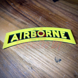 3D airborne tab displayed on wooden surface with bold yellow lettering and black background.