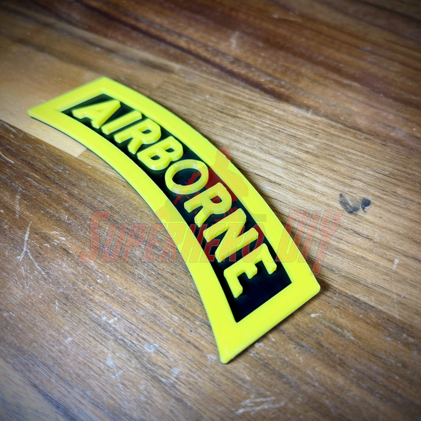3D airborne tab displayed on wooden surface with bold yellow letters and black background.