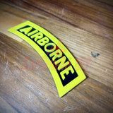 3D airborne tab displayed on wooden surface with bold yellow letters and black background.