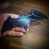 Hand holding 3D-printed BvS JL batarang prop made from PLA plastic in black, ideal for cosplay and costume use.