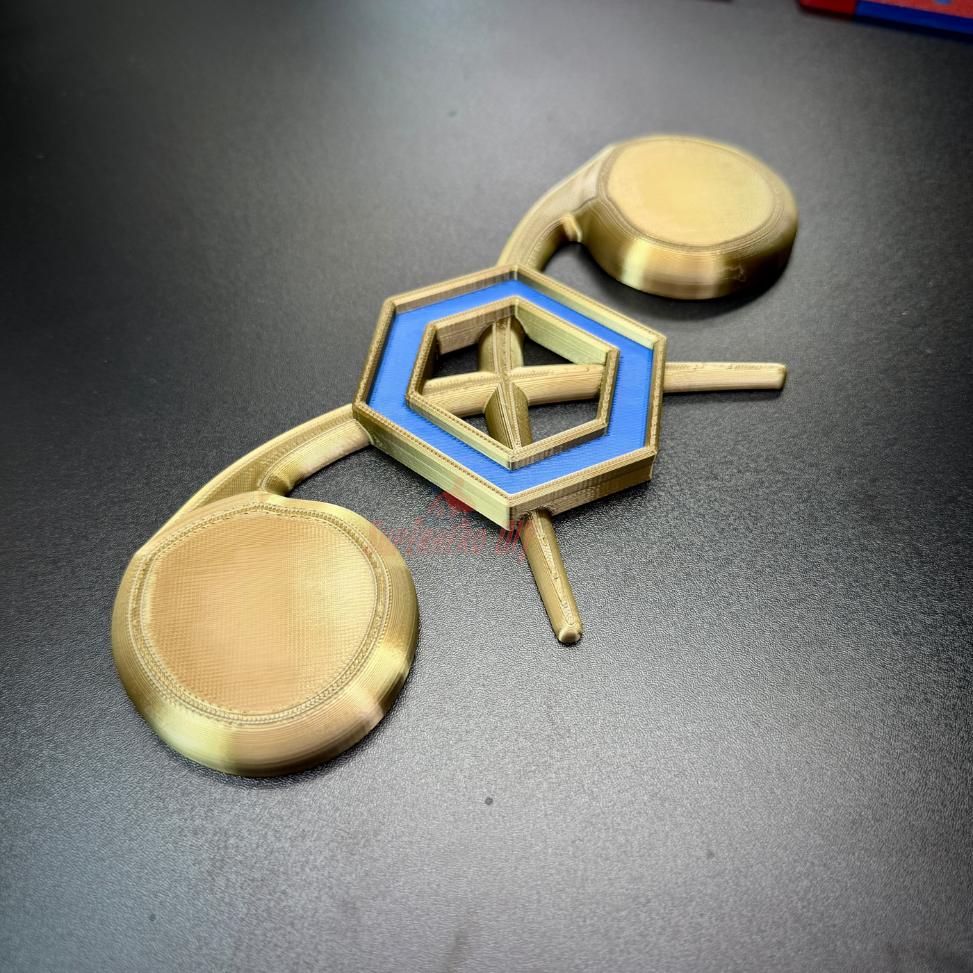 Chemical Corps insignia display showcasing a cobalt blue benzene ring on gold retorts against a black background.