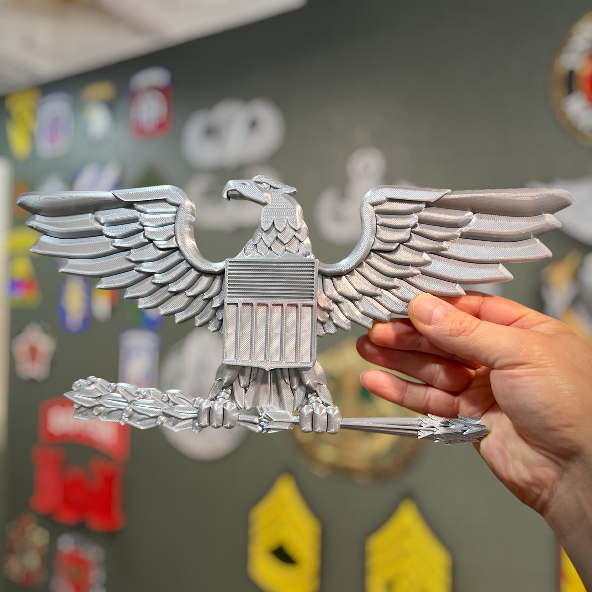 Hand holding a military officer rank insignia replica of an eagle, showcasing detailed craftsmanship and design.