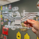 Hand holding a military officer rank insignia replica of an eagle, showcasing detailed craftsmanship and design.