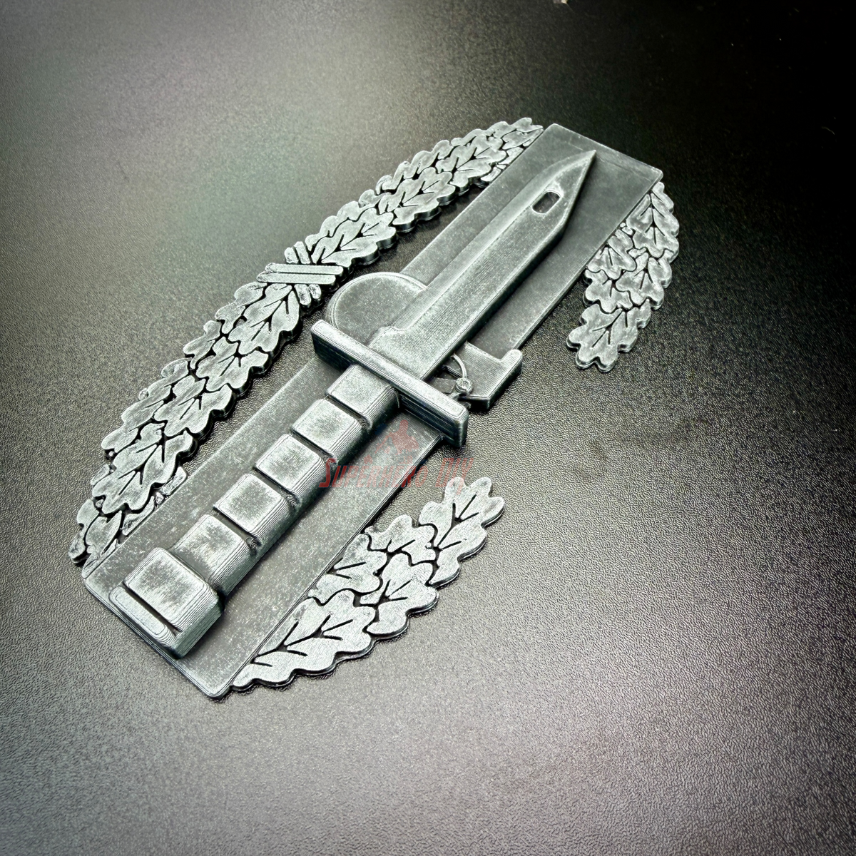 Combat Action Badge display insignia featuring a bayonet and oak wreath on a dark surface.