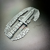 Combat Action Badge display insignia featuring a bayonet and oak wreath on a dark surface.