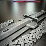Combat Action Badge display featuring detailed bayonet and oak wreath design on a black surface.