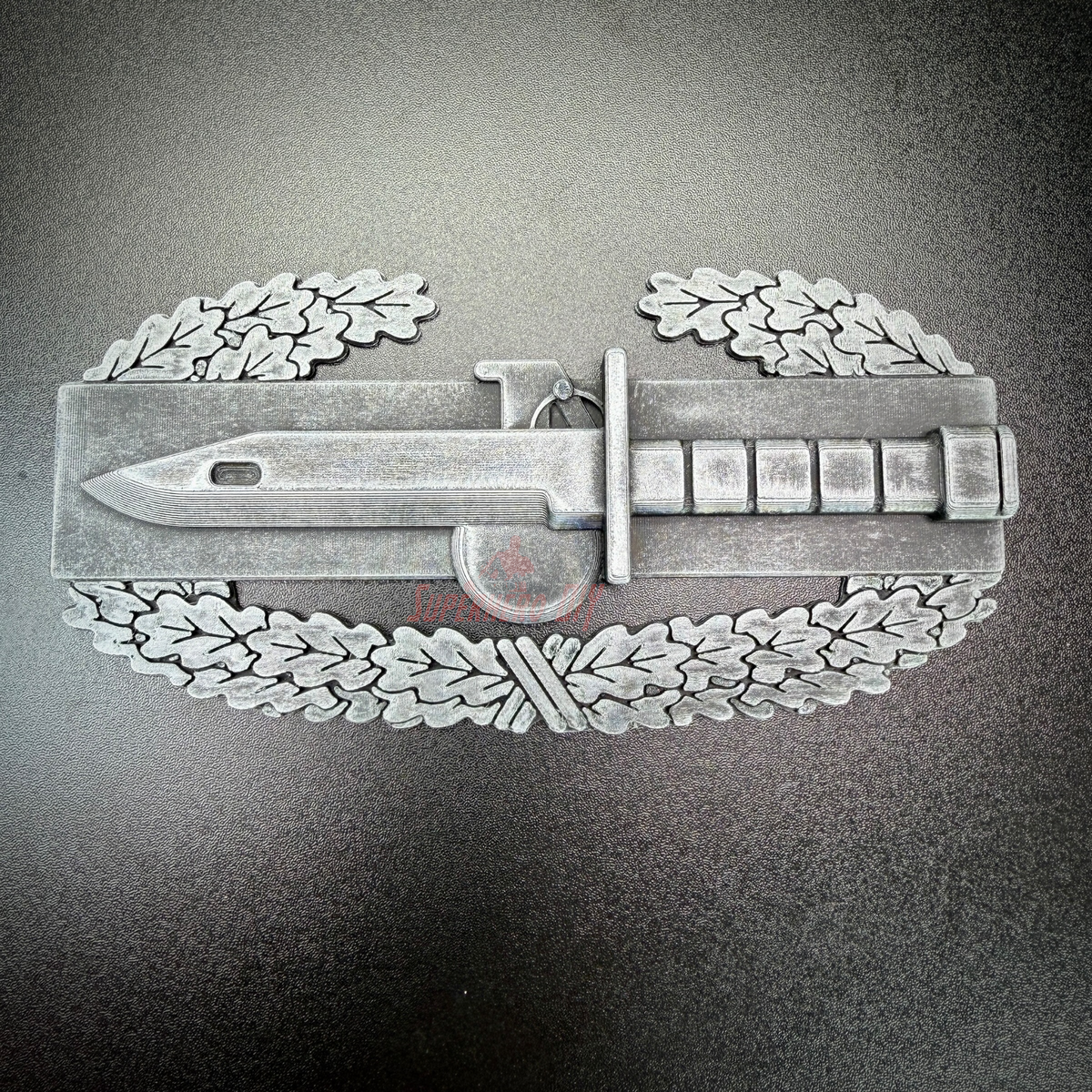 Combat Action Badge display insignia featuring a bayonet and oak wreath design.