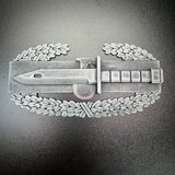 Combat Action Badge display insignia featuring a bayonet and oak wreath design.