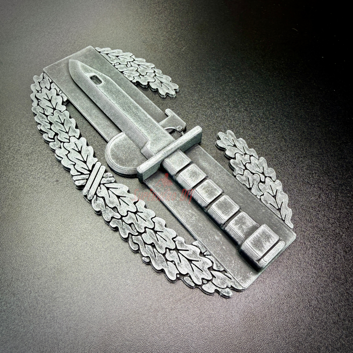 Combat Action Badge display insignia featuring a bayonet and oak wreath on a dark background.