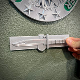 Expert Soldier Badge display insignia with M9 bayonet on a wall, showcasing its smooth design.