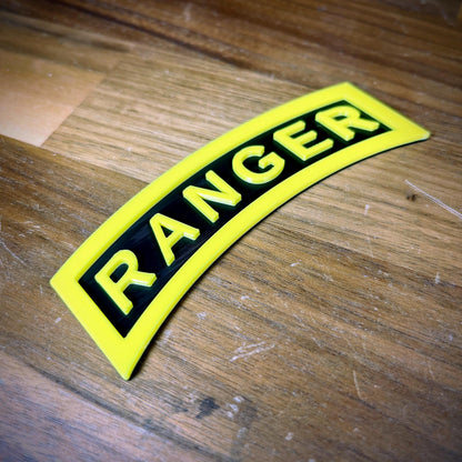 3D Army Ranger Tab replica in yellow-on-black design on a wooden surface, emphasizing its sharp detail and display quality.