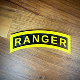 3D Army Ranger Tab replica displayed on wooden surface, showcasing its iconic yellow-on-black design.