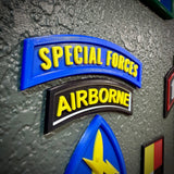 Special Forces display insignia featuring Special Forces and Airborne tabs on a textured wall background.