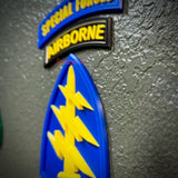 Special Forces display insignia featuring Airborne tab and arrowhead emblem on textured wall background.